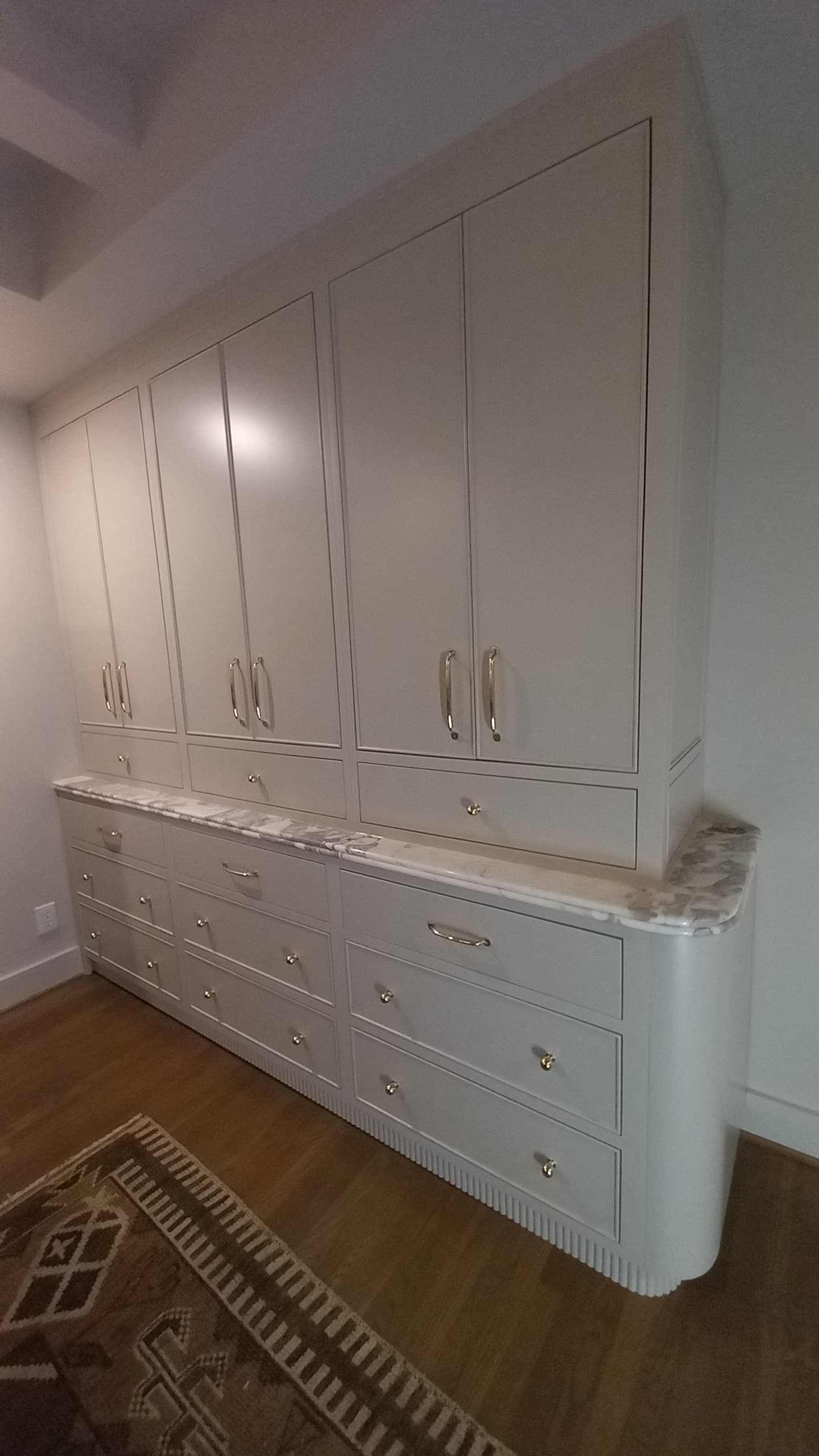 Cream custom storage cabinet with drawers, fluted rounded end, marble top, and brass pulls by Hdez Gabinets