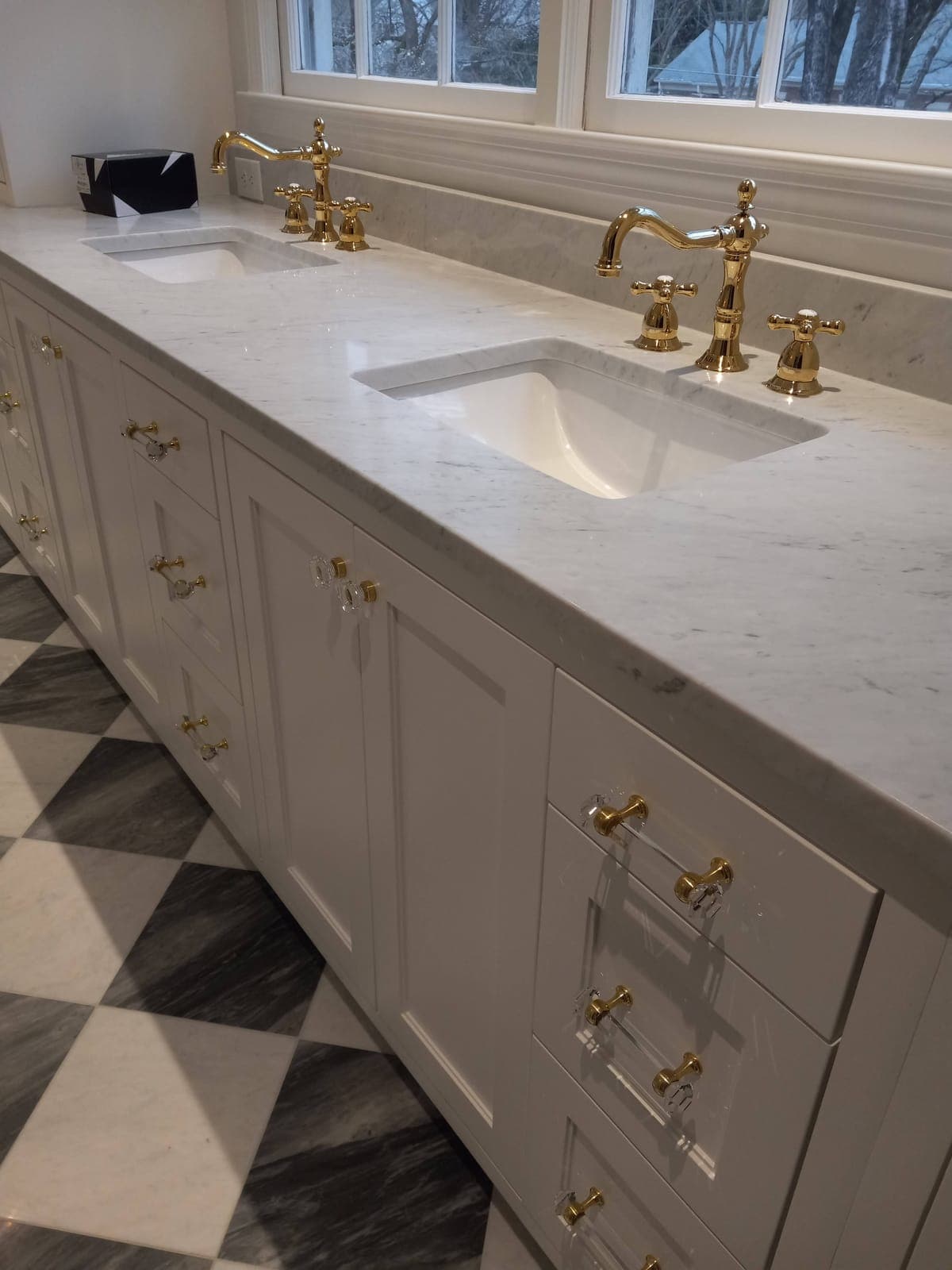 White custom double vanity with a marble top and brass faucets built by Hdez Gabinets