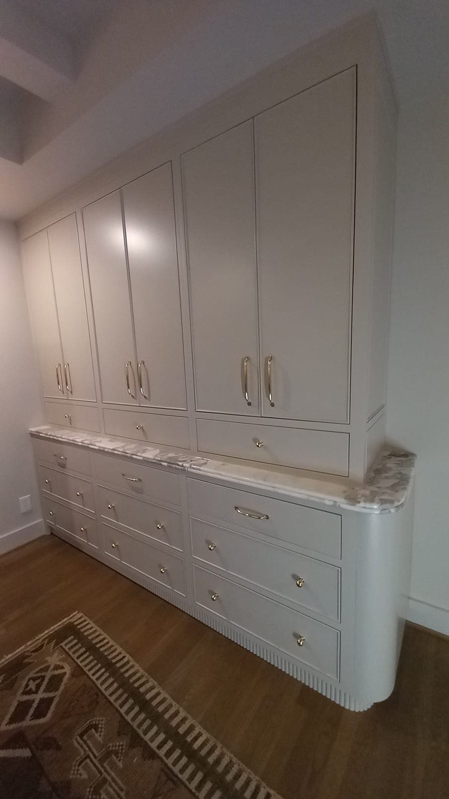 Cream built-in storage cabinet with drawers, marble top, and brass pulls by Hdez Gabinets