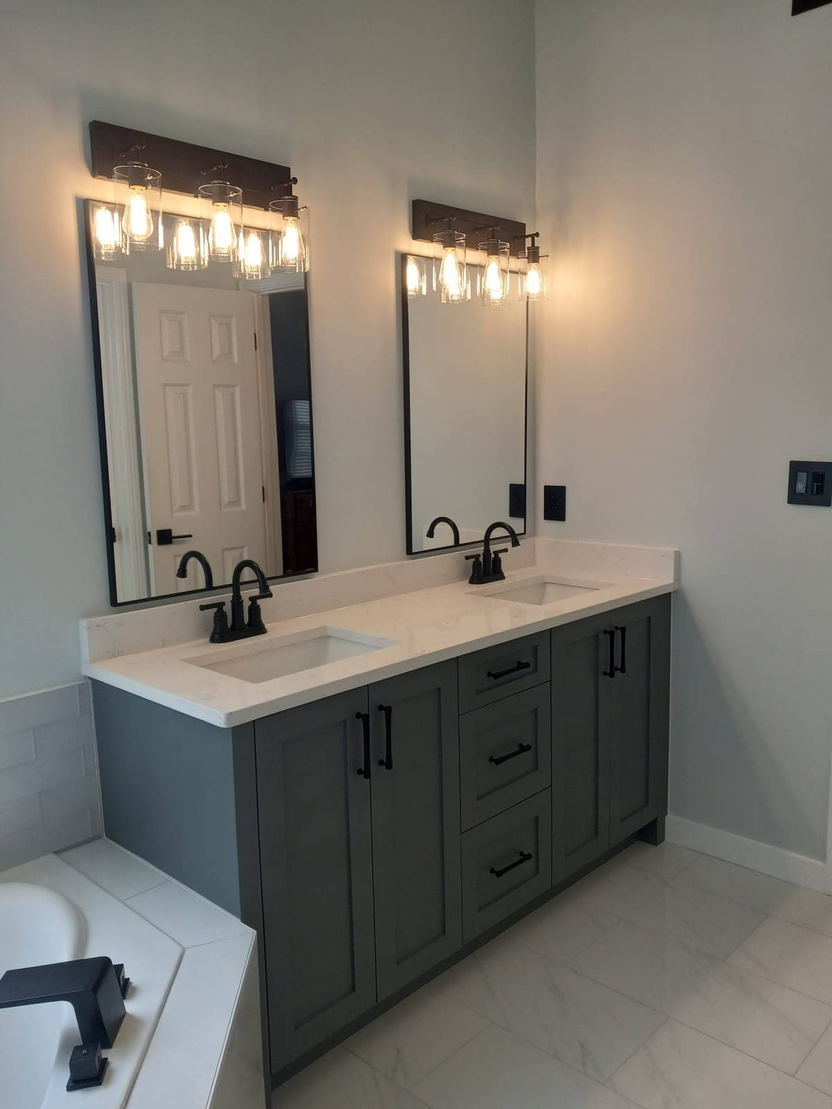 Gray-green custom double vanity with black hardware and a white quartz top by Hdez Gabinets
