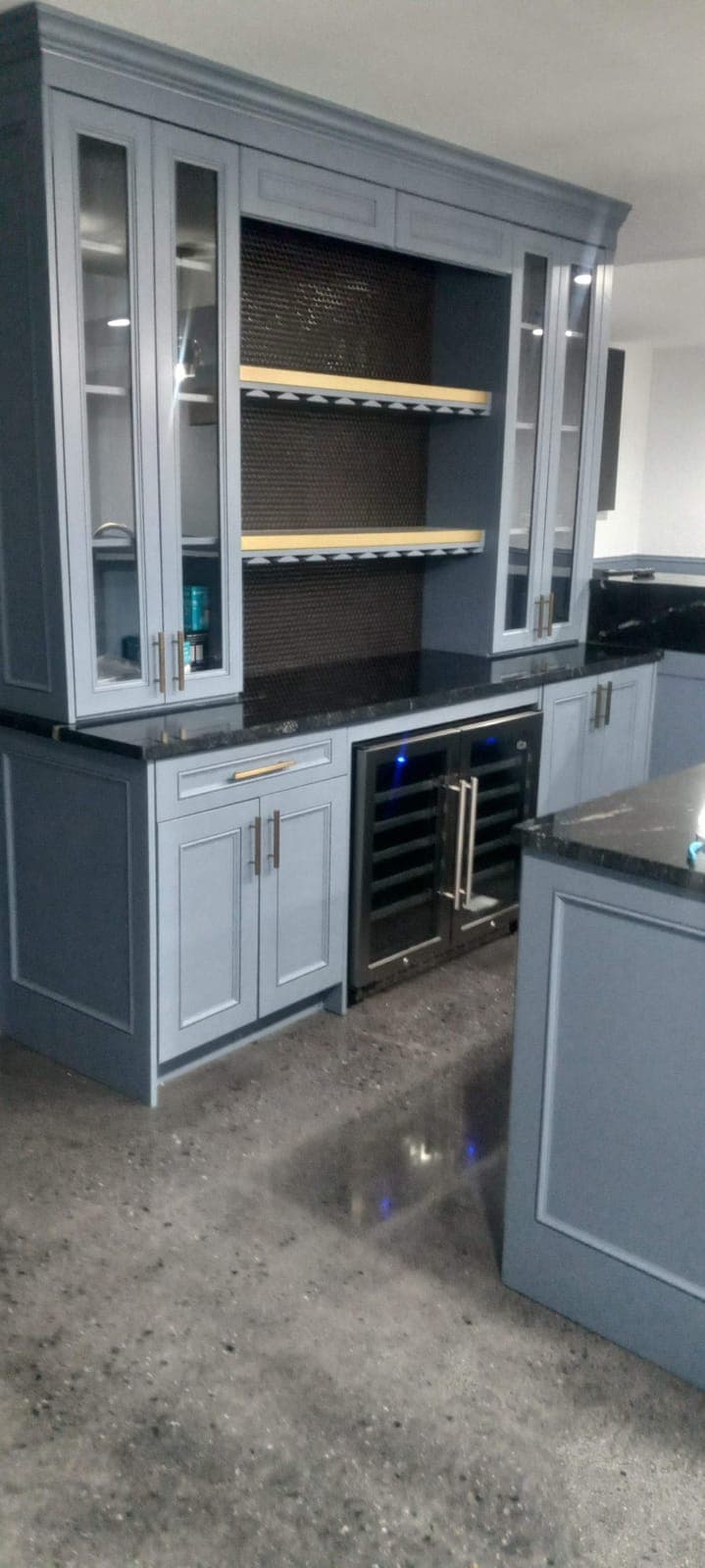 Home bar cabinetry with a wine fridge and lit glass-front cabinets by Hdez Gabinets