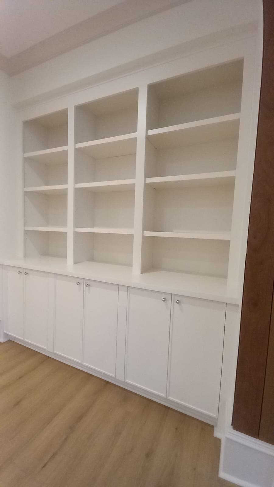 White built-in bookshelves with lower cabinets, built by Hdez Gabinets