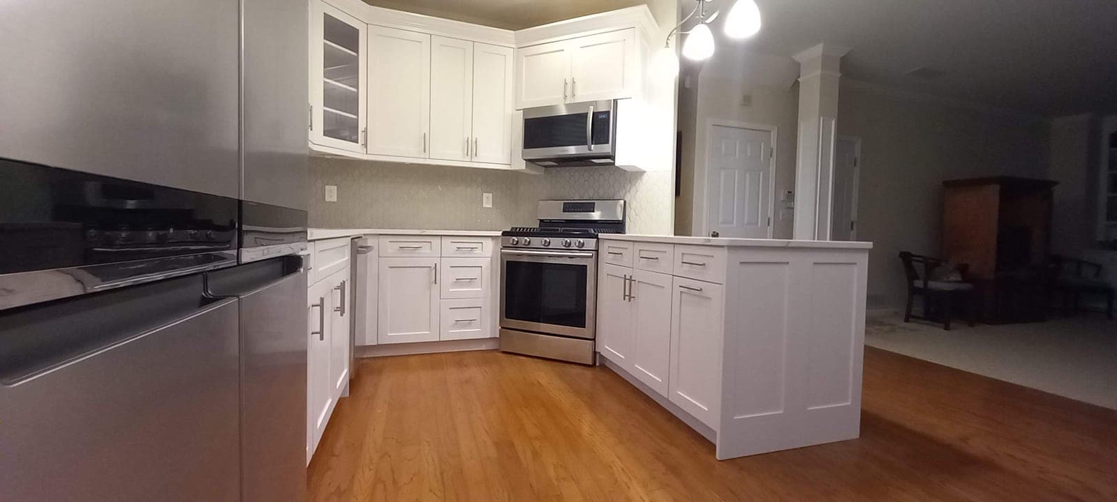 L-shaped white custom kitchen with a gas range and stainless appliances, built by Hdez Gabinets