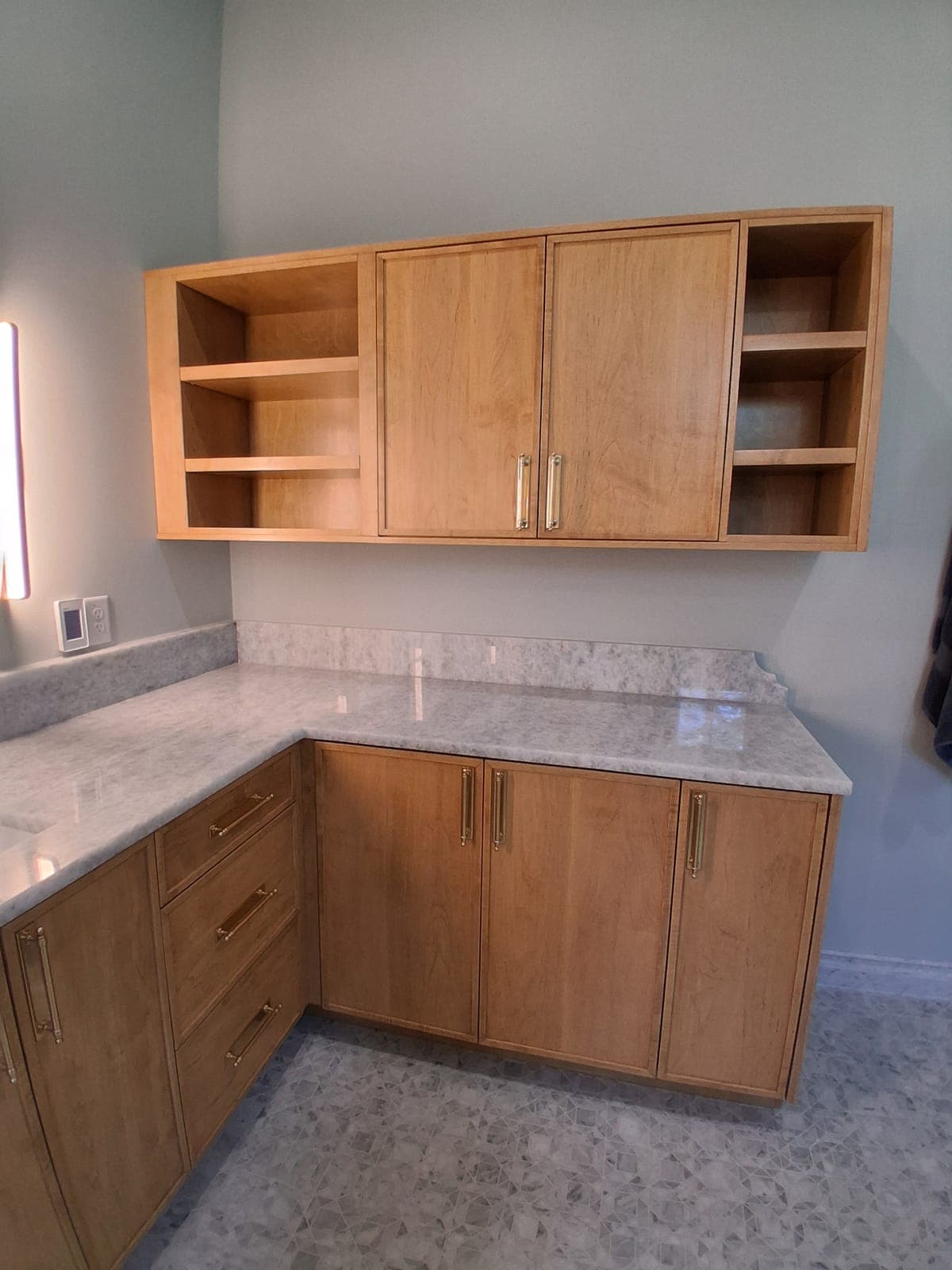 Custom wood corner vanity with open upper shelves and a stone top built by Hdez Gabinets