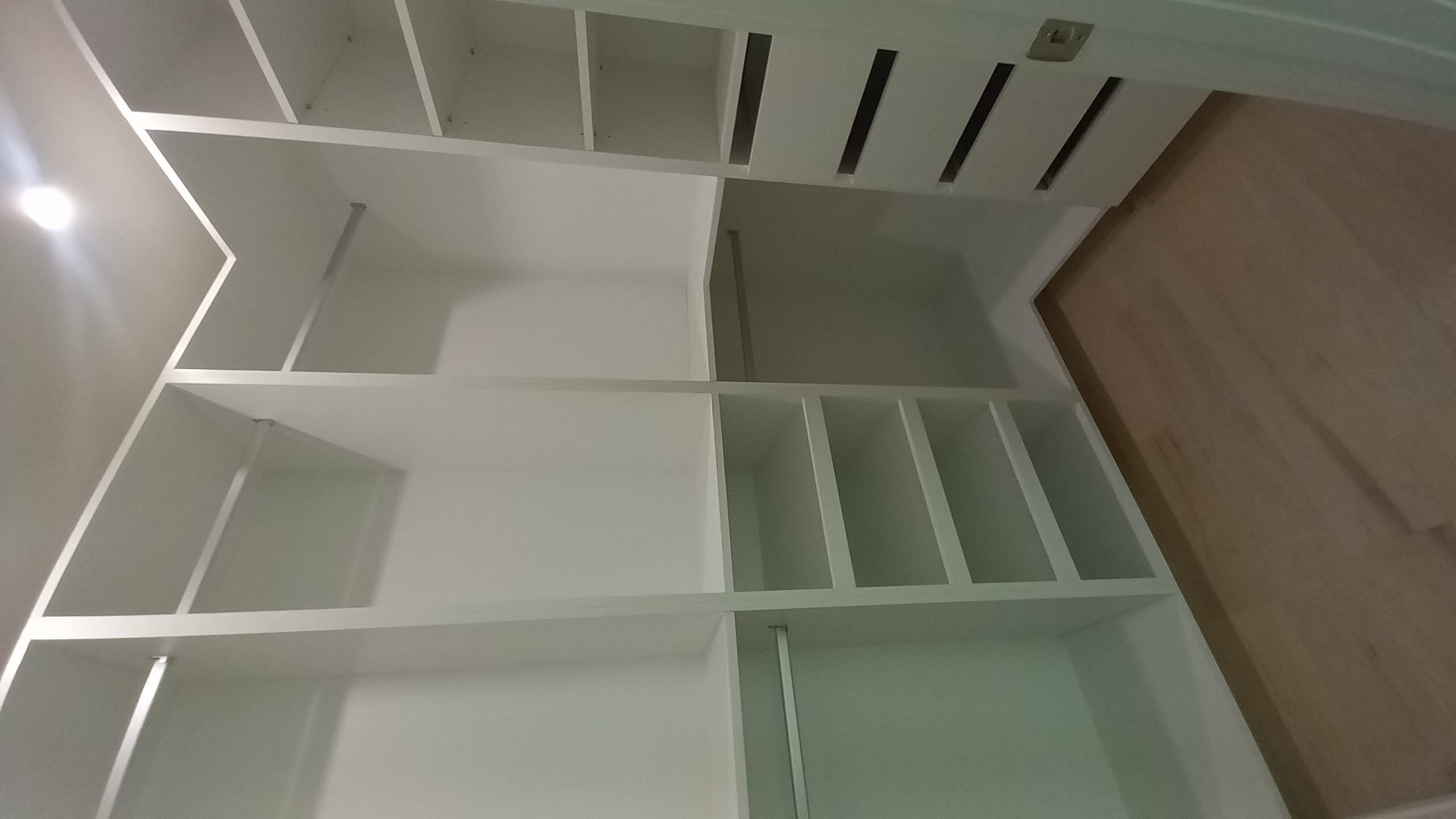 L-shaped walk-in closet with hanging rods, shoe shelves, and drawers built by Hdez Gabinets